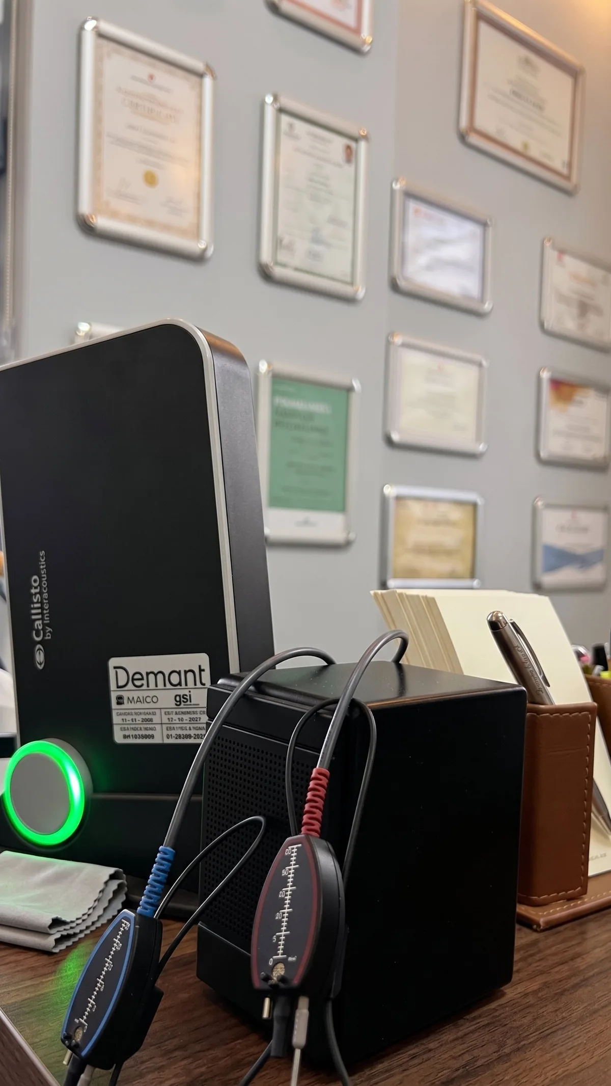 Çankaya İşitme Cihazı Merkezi'nde Interacoustics Callisto REM ölçüm cihazı — yapım aşamasında, mavi ve kırmızı prob mikrofonlar görünüyor, arka planda klinik sertifikalar